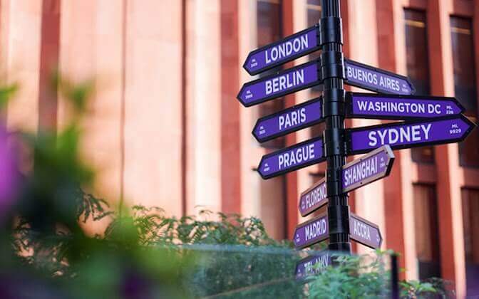 Directional arrow signs pointing to NYU global sites including London, Berlin, and Paris