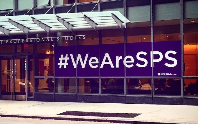 NYU School of Professional Studies building exterior with sign in window saying #WeAreSPS